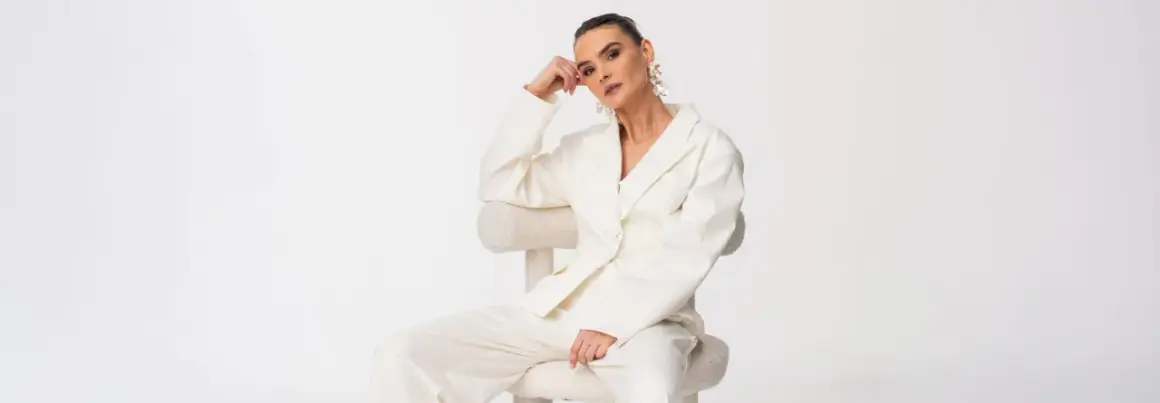 Elegancka biała stylizacja, idealna odpowiedź na pytanie jak się ubrać na komunię. Długie spodnie i marynarka tworzą szykowny komplet.