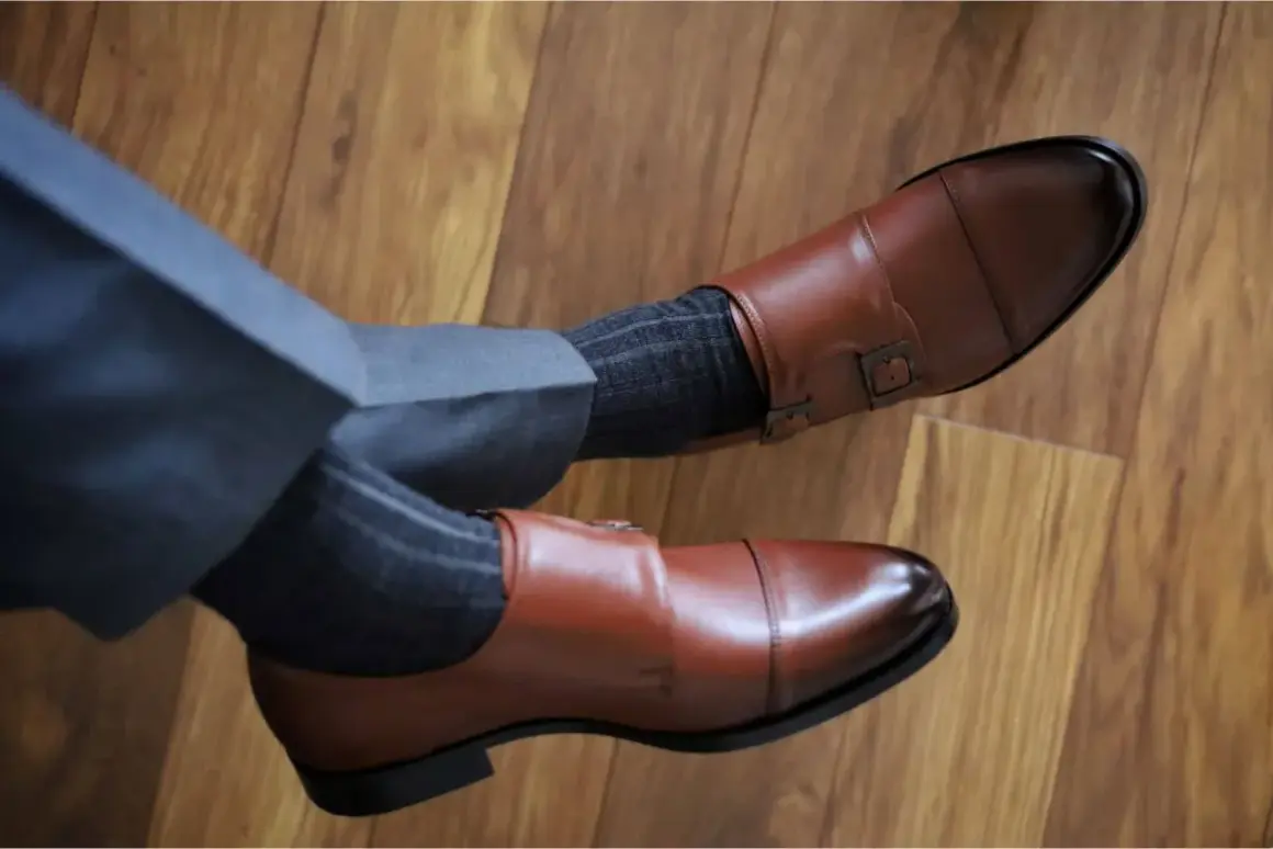 Granatowy garnitur, brązowe buty monk strap i grafitowe skarpetki w prążki tworzą elegancki zestaw.